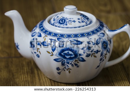 Beautiful vintage white and blue tea-pot with white flowers on the background