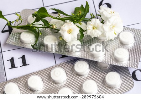 Gentle white flowers with blisters of pills on a calendar