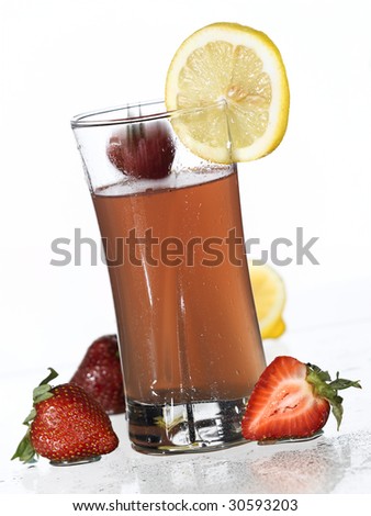 A glass of strawberry lemonade with a strawberry about to splash into it.