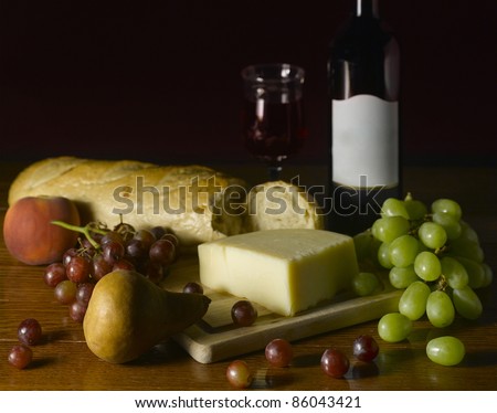 Wine, Cheese, Bread and Fruit arranged on a table.