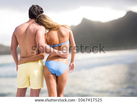 Back of couple in swimsuits against blurry beach