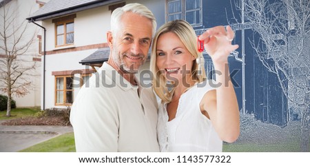 Happy couple showing their new house key against pretty house with a blue and white filter