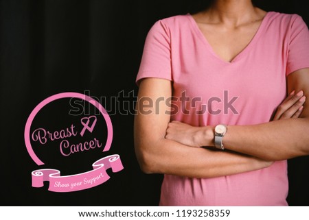 Heart shape ribbon with breast cancer text against women in pink for breast cancer focus on crossed arms