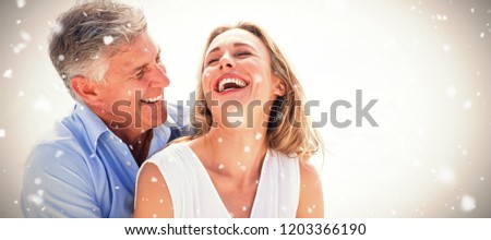 Happy couple laughing together against snow falling