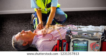 Paramedic using an external defibrillator on an unconscious patient lying on carpet