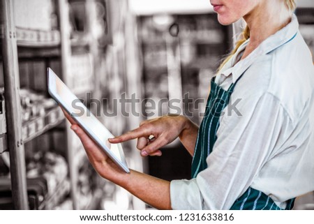 Mid-section of female staff using digital tablet in super market