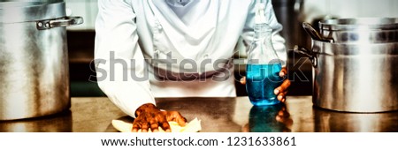 Chef cleaning kitchen counter with a bottle of solution and a rag