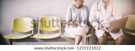 Doctor and patient discussing over laptop in hospital waiting room