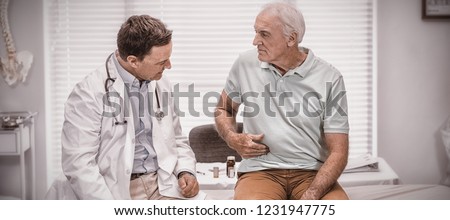Senior man showing stomach ache pain to doctor in clinic