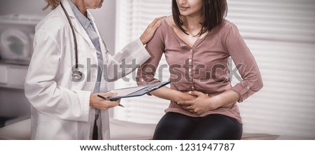 Patient suffering from stomach ache while consulting doctor in clinic