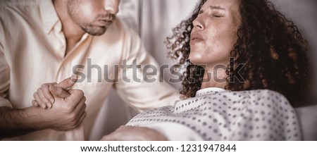 Man comforting pregnant woman during labor in ward of hospital