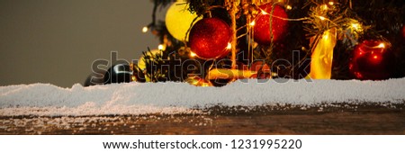 Wooden table with snow against christmas garlands on a pine