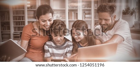 Happy family using technologies while sitting on sofa at home