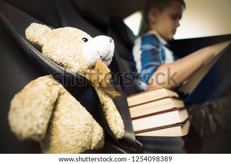 Teenage boy reading book in the back seat of car