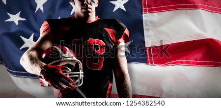 American football player holding rugby helmet against full frame of american flag