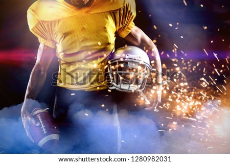 Mid section of male athlete with American football and helmet against firework bursting sparkle background