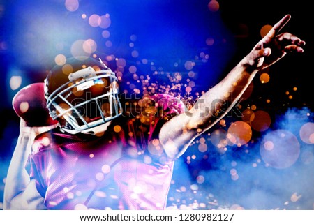 American football player with ball pointing against firework bursting sparkle background
