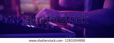 Mid section of male dj mixing music on mixing console in bar