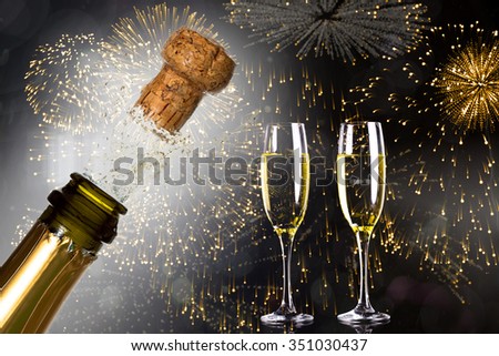 Close up of champagne cork popping against colourful fireworks exploding on black background