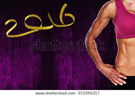 Female bodybuilder posing with hands on hips mid section against black background