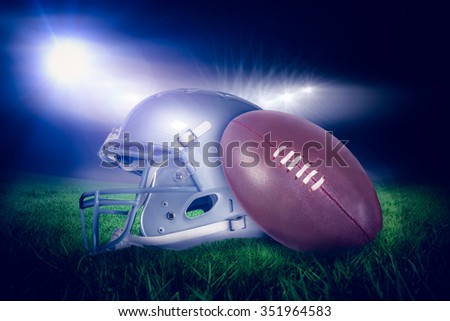 American football helmet and ball against rugby stadium