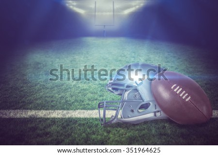 American football helmet and ball against american football pitch
