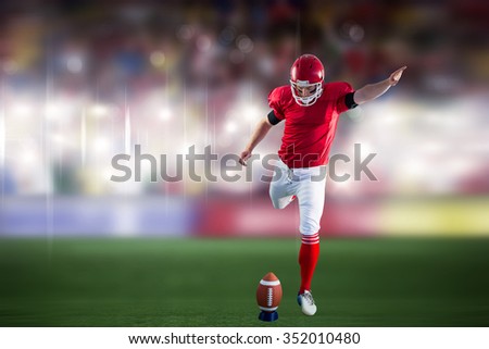 American football player kicking football against sports arena