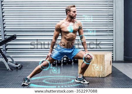 Muscular man doing leg stretchings against fitness interface