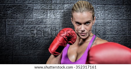 Portrait of female boxer with fighting stance against grey brick wall