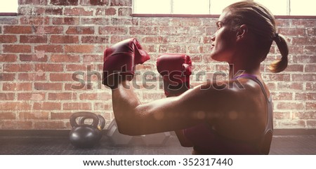 Side view of female boxer with fighting stance against gym
