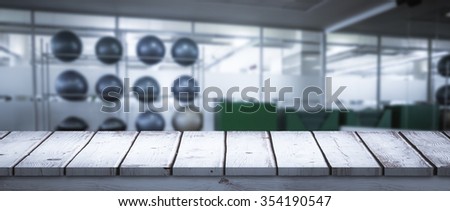 Wooden desk against large empty fitness studio with shelf of exercise balls
