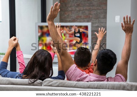Athletic man practicing show jumping against happy family rejoicing while watching tv on the sofa
