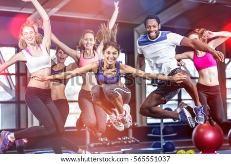 Fit group smiling and jumping in gym