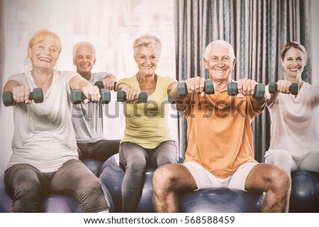 Portrait of seniors using exercise ball and weights during sports class