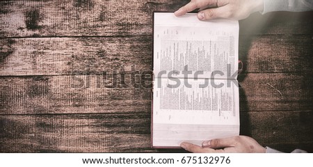 Cropped hands of man holding bible on wooden table