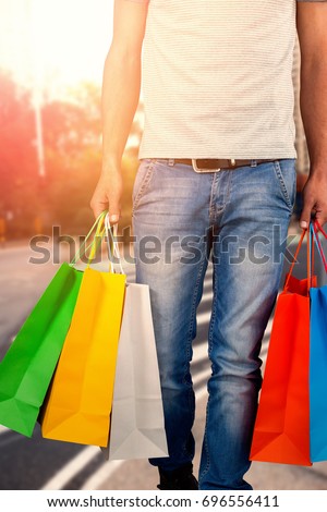 Low section of man carrying colorful shopping bag against white background against new york street