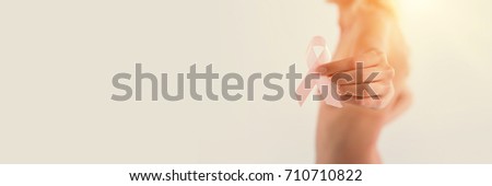 Mid section of shirtless woman holding pink breast cancer awareness ribbon