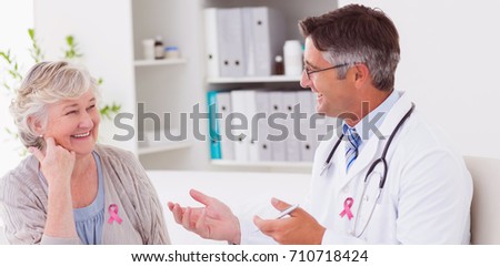 Breast cancer awareness message against doctor discussing with senior patient at table