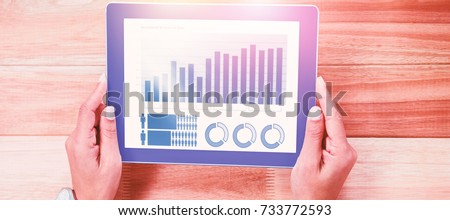 Blue graphics on white background against overhead of feminine hands using tablet