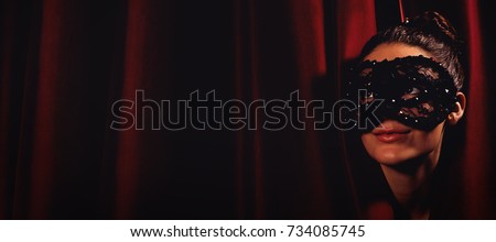 Female artist in mask peeking through curtain at stage