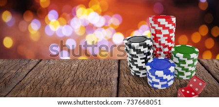 Stack of colorful casino tokens by red dice against composite image of table