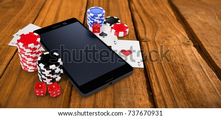 Mobile phone with playing cards and casino tokens against high angle of wooden planks
