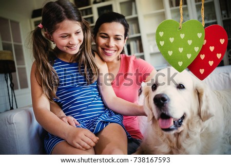 Cute heart decorations against mother and daughter sitting with dog in living room