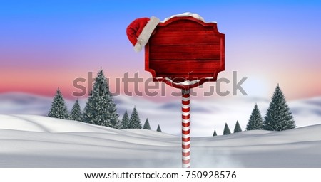 Digital composite of Wooden signpost in Christmas Winter landscape and Santa hat