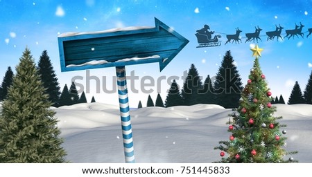 Digital composite of Wooden signpost in Christmas Winter landscape with Christmas tree and Santa's sleigh and reindeers
