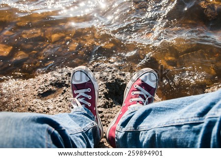 feet in sneakers on the sea