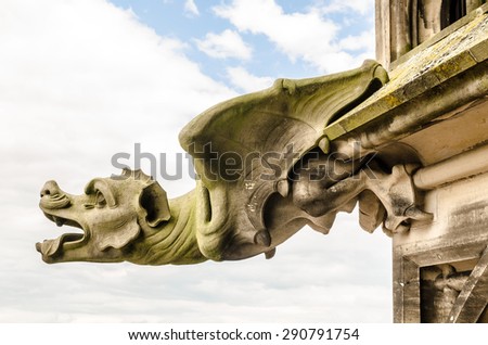 Gargoyle on a gothic cathedral, detail of a tower and clouds on the background