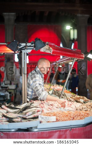 VENICE, ITALY - APRIL 1, 2014: An unidentified merchant works at the fish market and other unidentified people around, on April 1, 2014 in Venice, Italy