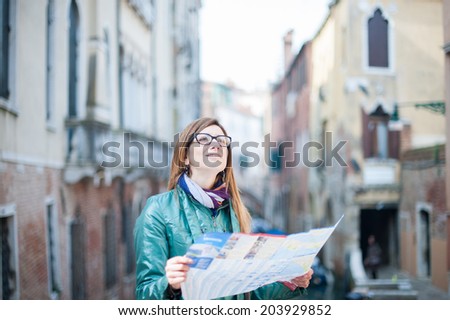 A beautiful young woman consulting a map and looking up in Venice.