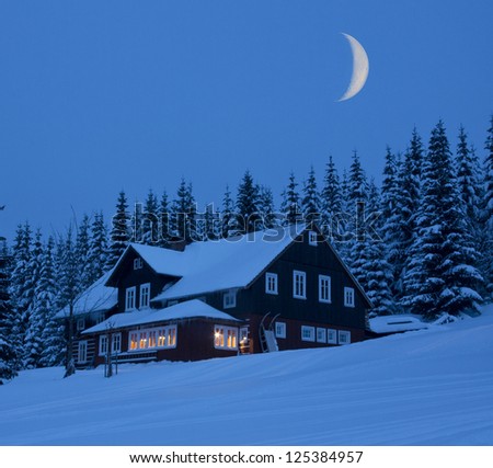 Mountain cottage in winter moonlit night